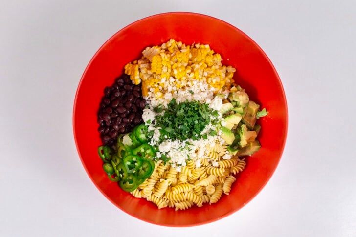 An overhead photo of a large red mixing bowl containing all the ingredients for the salad, unmixed.