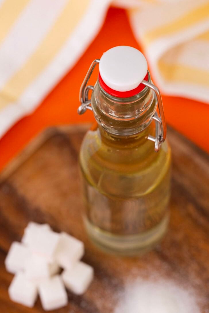 Simple syrup in a bottle on a table next to a pile of sugar cubes