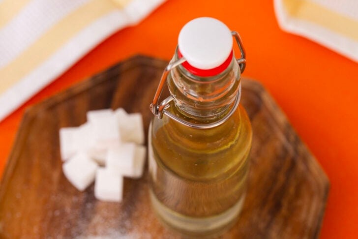 A landscape photo of a bottle of simple syrup next to a pile of sugar cubes.