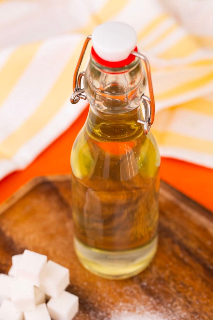 Simple syrup in a bottle next to a pile of sugar cubes