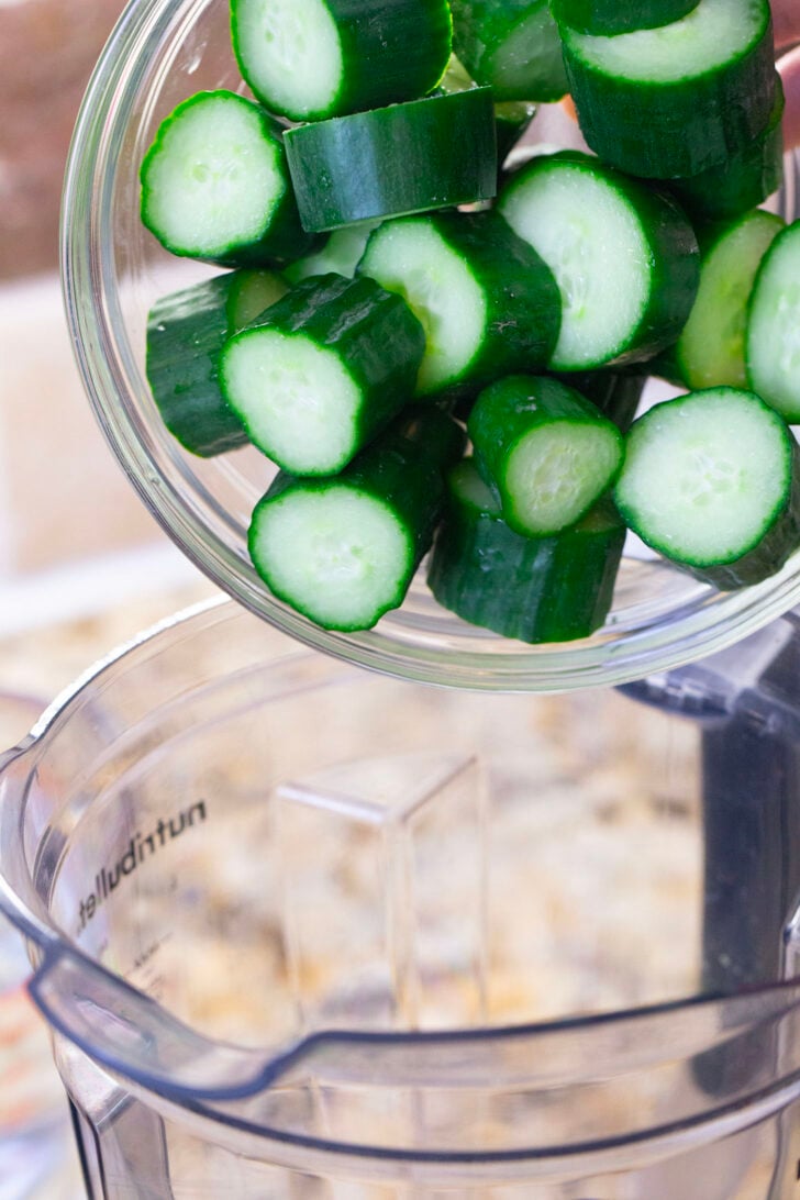 Chopped cucumber being poured into a blender.