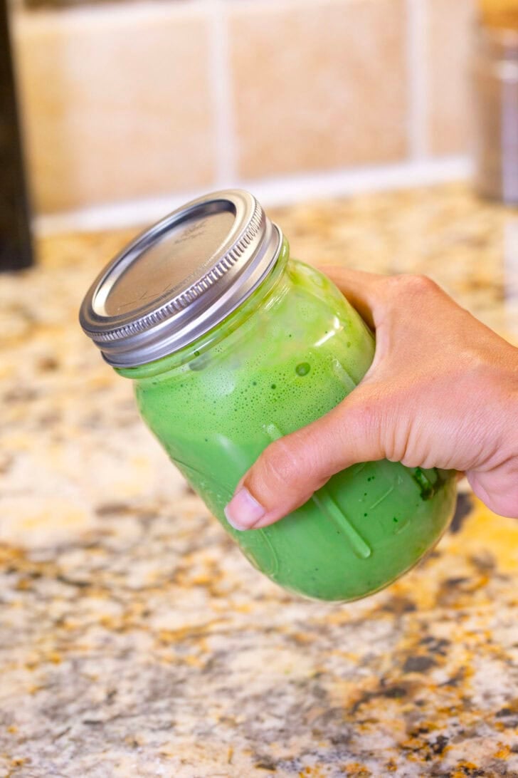 A shot of Alyssia shaking the sealed glass jar with the iced matcha latte ingredients inside.