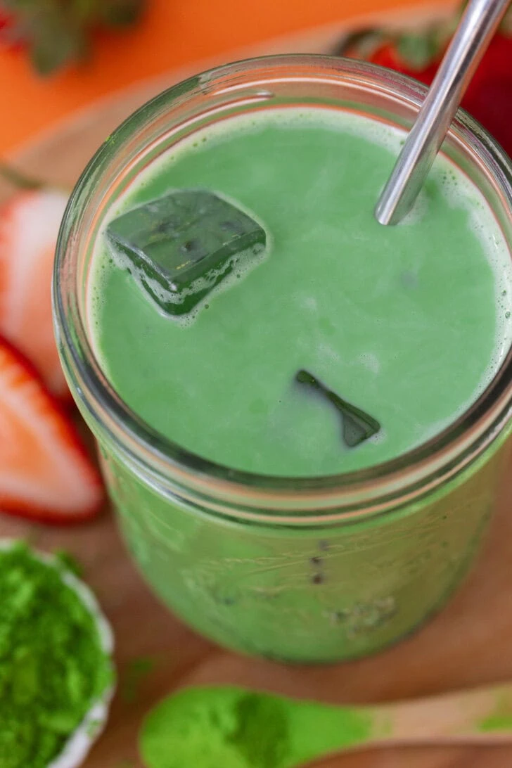 An overhead shot of an iced matcha latte in a glass jar.