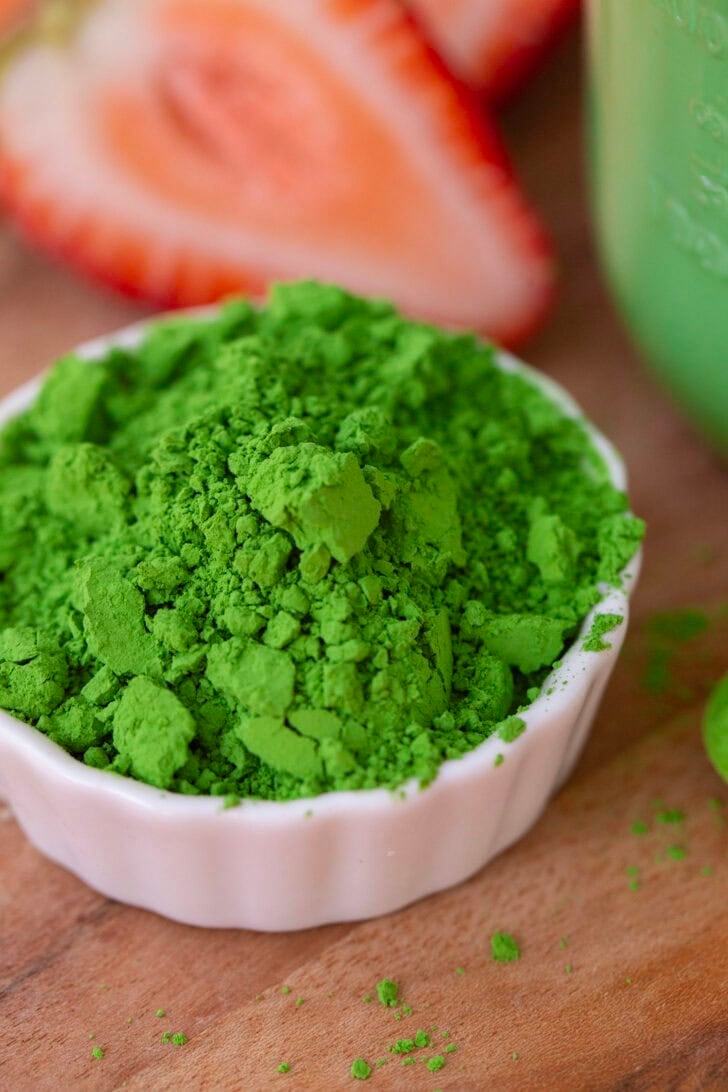 A small white bowl filled with bright green matcha powder.
