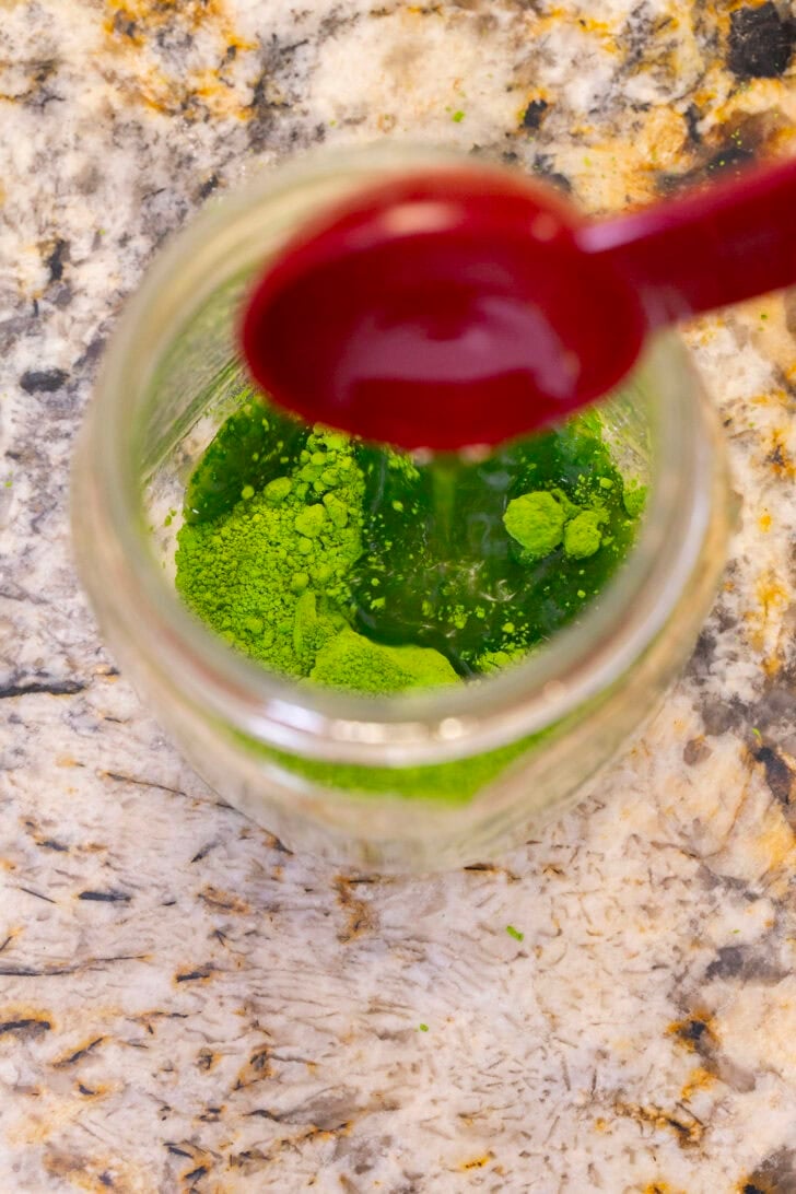 An overhead shot of adding optional sweetener to the iced matcha latte.