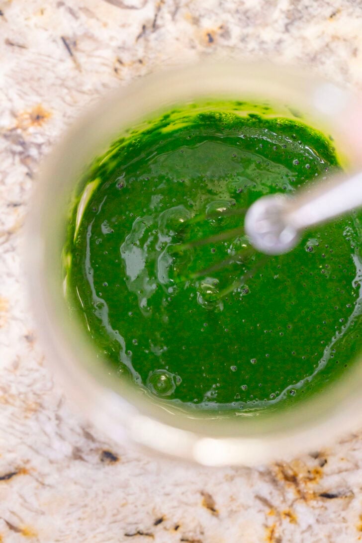 An overhead shot of whisking the iced matcha latte ingredients in a glass jar.