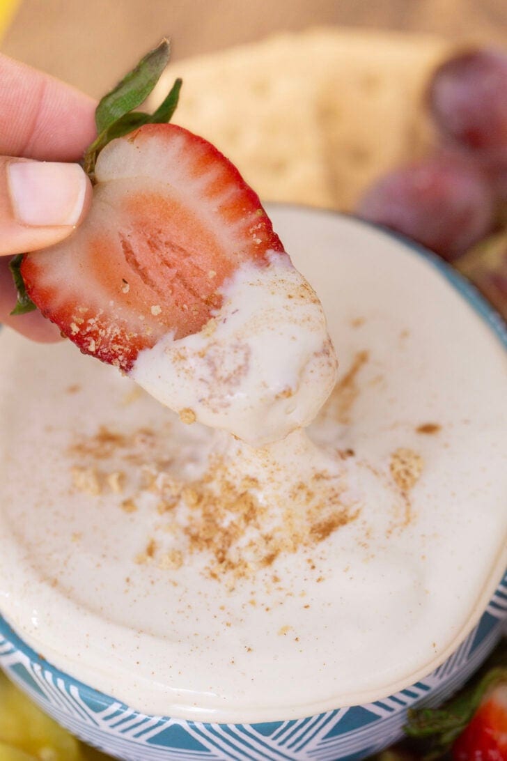 Dipping a strawberry into no bake cheesecake dip.