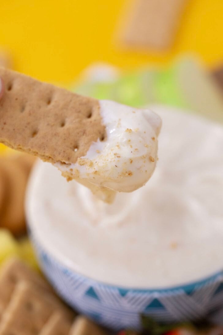 Dipping a piece of a graham cracker into no bake cheesecake dip.