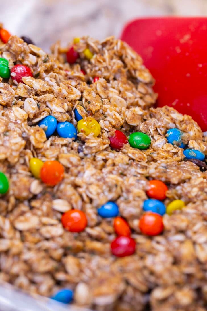 A spatula mixing the protein ball mixture in a large glass bowl.