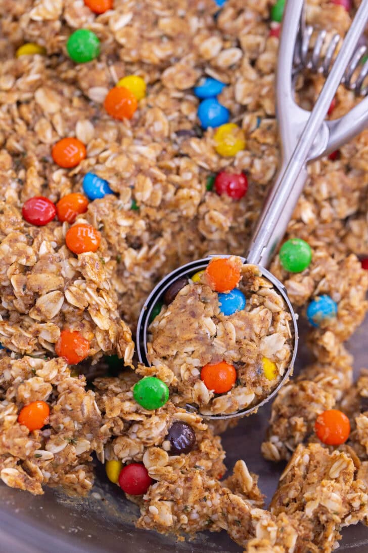 Using a metal cookie scoop to scoop out balls of the protein ball mixture.