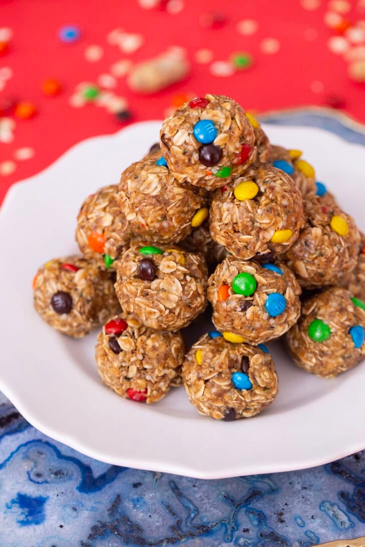 A pile of protein balls without dates on a white plate, sitting on a red table setting.