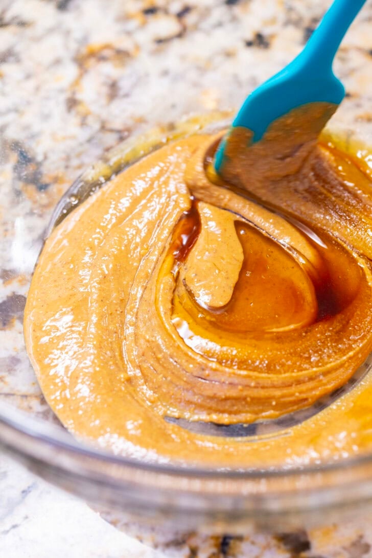 Using a spatula to stir together the peanut butter, honey, vanilla extract, and salt in a glass mixing bowl.
