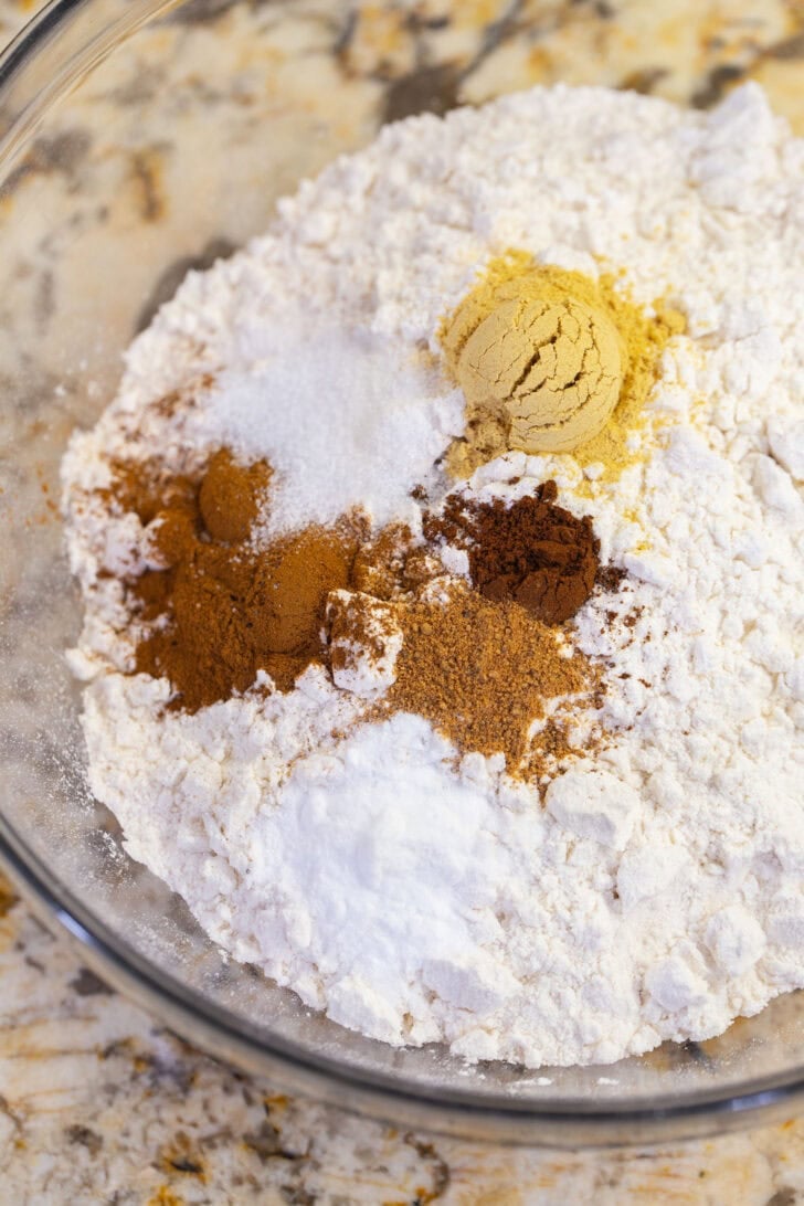 Flour, ground ginger, cinnamon, cloves, nutmeg, baking soda, and salt in a glass bowl before whisking.
