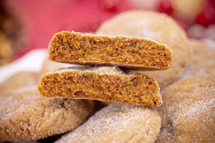 A gingerbread cookie broken in half to show its soft, chewy center, stacked on top of more cookies.