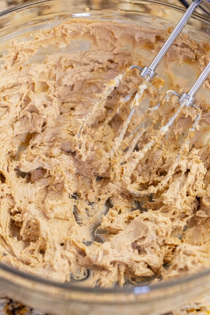 Butter and dark brown sugar beaten until smooth and fluffy, with the hand mixer beaters resting in the bowl.