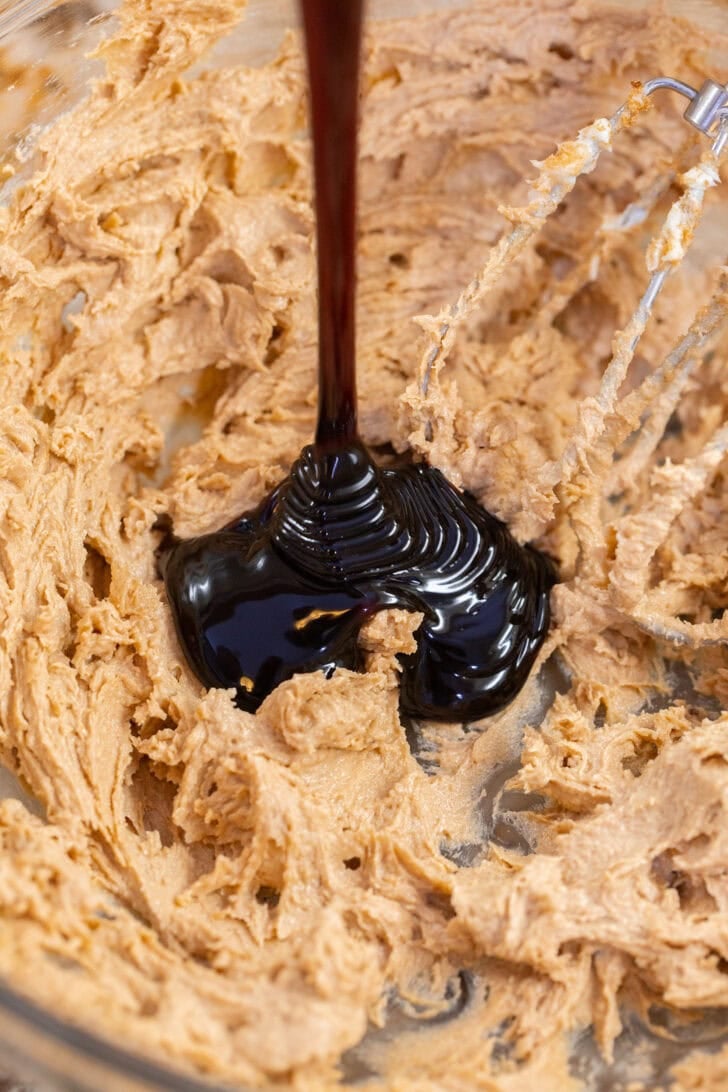 Molasses pouring into creamed butter and brown sugar for eggless gingerbread cookies.