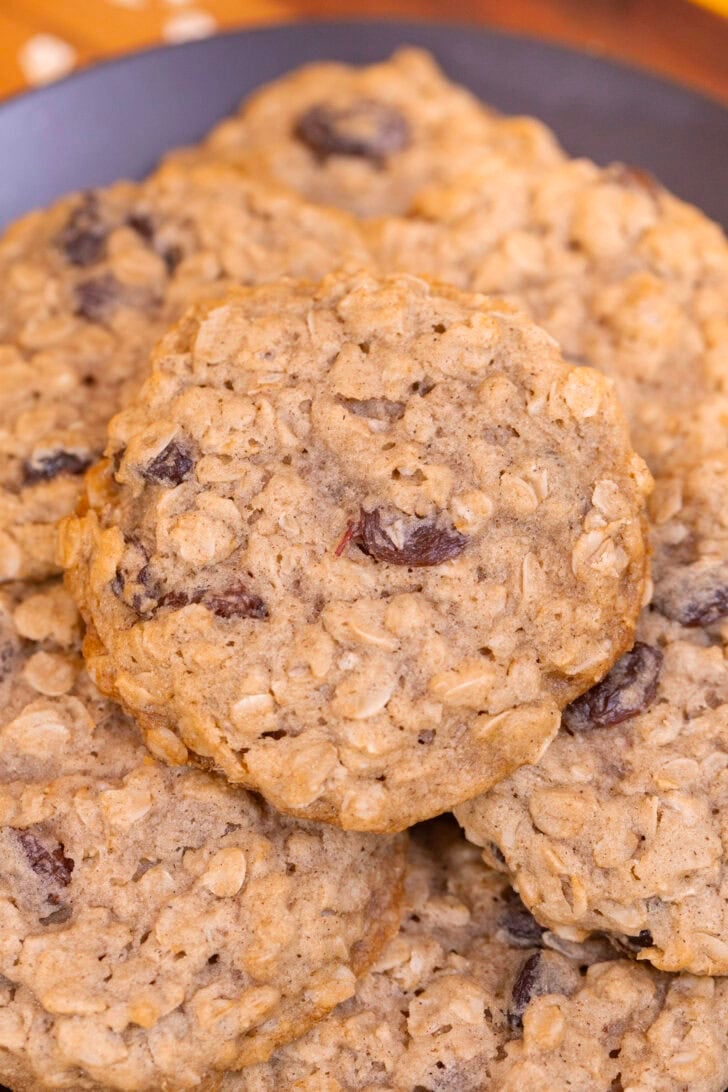 A close-up of a soft, chewy oatmeal raisin cookie with plump raisins and golden edges.