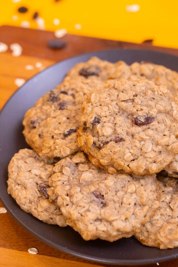 Soft eggless oatmeal raisin cookies with lightly crisp edges piled on a dark plate.
