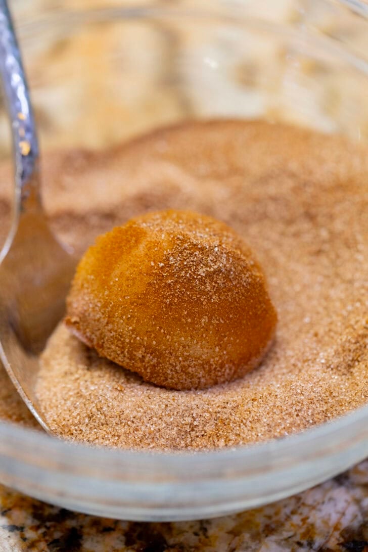 A ball of snickerdoodle dough rolled in cinnamon sugar until fully coated.