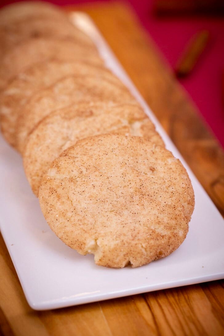 A close-up of soft, cinnamon-sugar-coated eggless snickerdoodles lined up on a white platter.