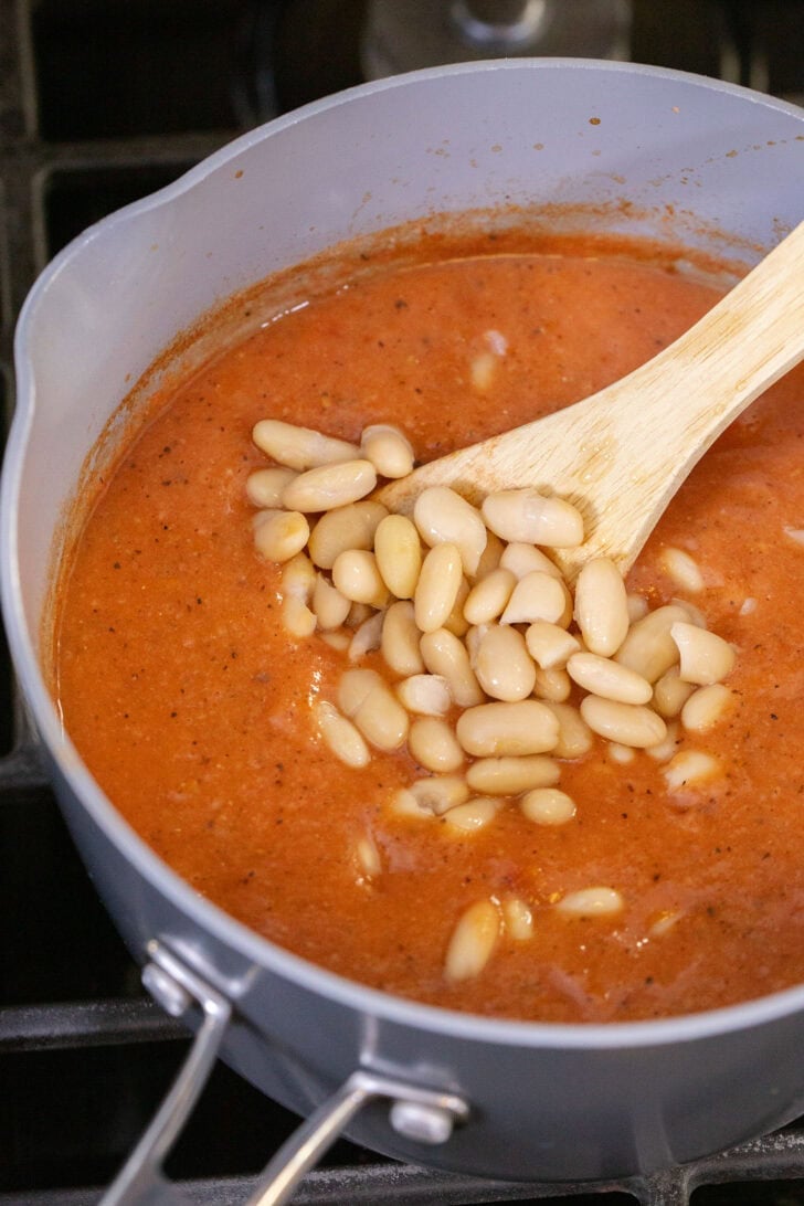 Adding additional whole cannellini beans to blended 3-ingredient white bean tomato soup.